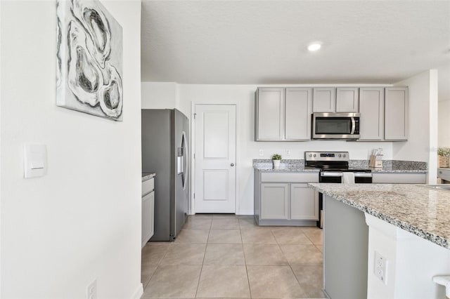 kitchen featuring light tile patterned flooring, gray cabinets, and appliances with stainless steel finishes