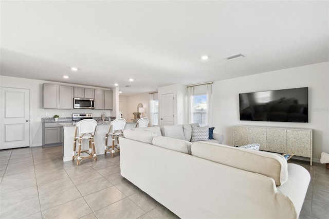 living area featuring light tile patterned floors, visible vents, recessed lighting, and baseboards