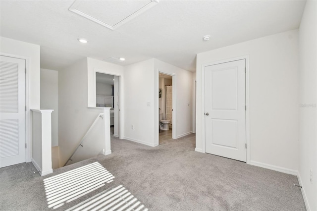 empty room with attic access, baseboards, and carpet floors