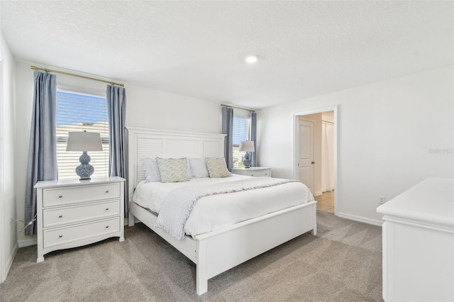 bedroom with light colored carpet, a textured ceiling, and baseboards