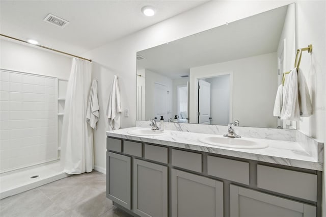 bathroom featuring double vanity, visible vents, a stall shower, and a sink