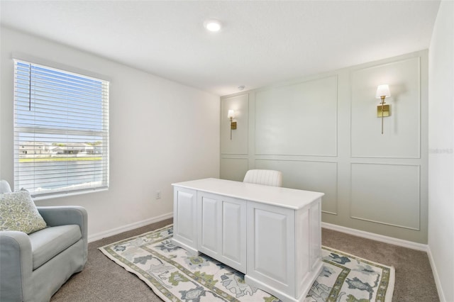 office area featuring baseboards, light colored carpet, and a decorative wall