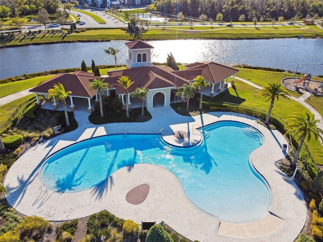 pool with a patio, a lawn, and a water view