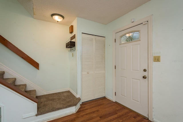 entrance foyer featuring baseboards, a textured ceiling, wood finished floors, and stairs