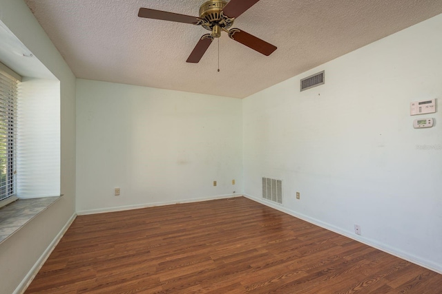 spare room featuring wood finished floors, visible vents, and a textured ceiling