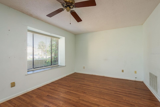 empty room with visible vents, a textured ceiling, baseboards, and wood finished floors