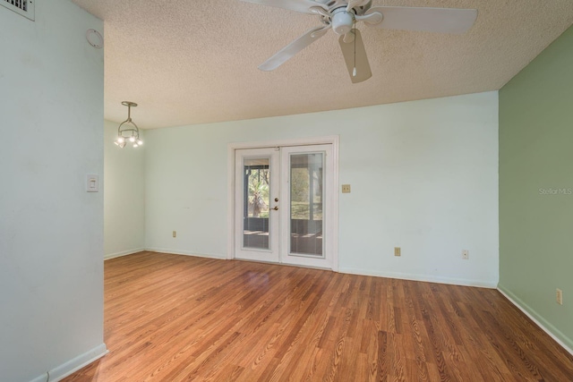 unfurnished room featuring visible vents, baseboards, a textured ceiling, and wood finished floors