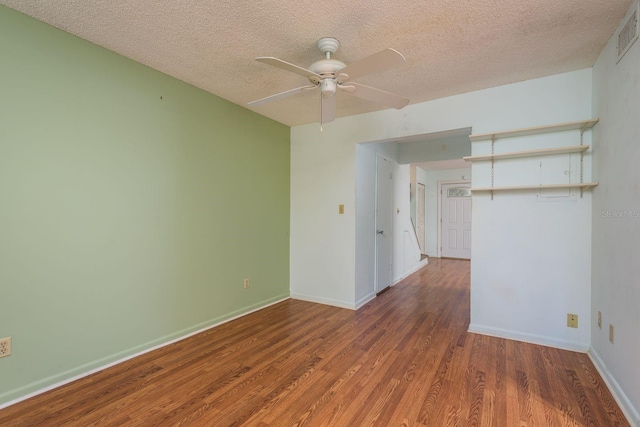 empty room with a textured ceiling, wood finished floors, baseboards, and ceiling fan