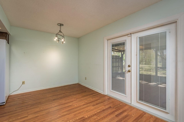 empty room with wood finished floors, baseboards, french doors, and a textured ceiling