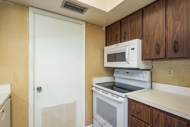 kitchen with visible vents, white appliances, light countertops, and wallpapered walls