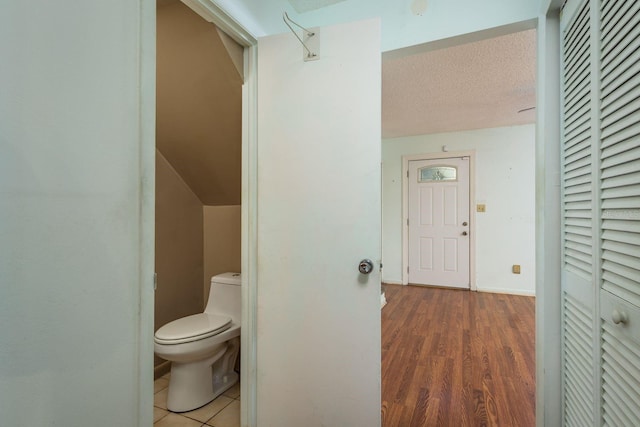 bathroom featuring toilet, wood finished floors, baseboards, and a textured ceiling