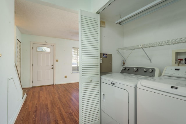 washroom featuring washer and dryer, a textured ceiling, wood finished floors, baseboards, and laundry area