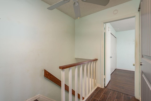 stairway featuring ceiling fan, baseboards, a textured ceiling, and wood finished floors