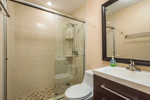 full bathroom featuring a tile shower, toilet, and vanity