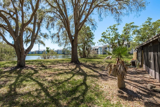 view of yard with central air condition unit and a water view