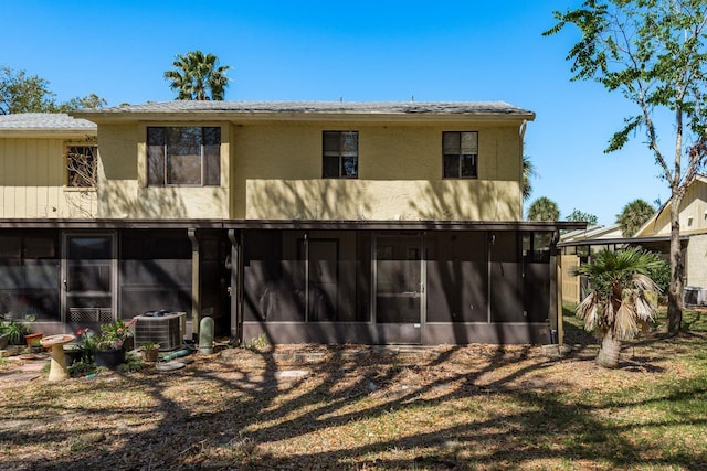 back of property featuring stucco siding, central AC unit, and a sunroom