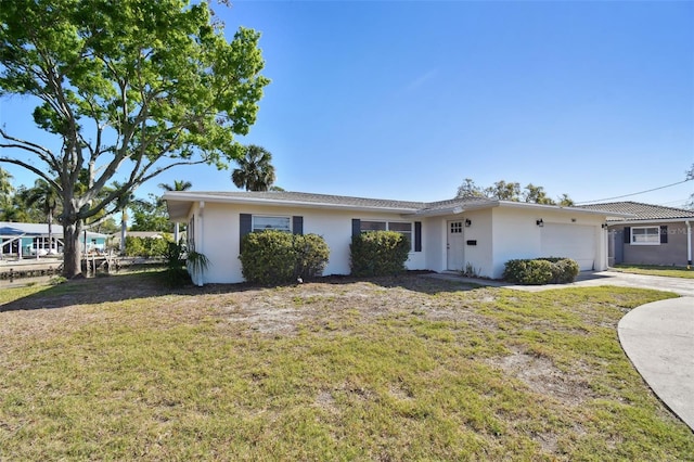 ranch-style home featuring stucco siding, an attached garage, driveway, and a front lawn