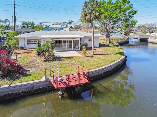 dock area featuring central air condition unit, a water view, and a lawn