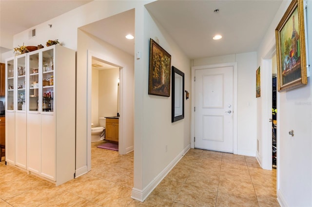 corridor featuring recessed lighting, baseboards, and light tile patterned floors