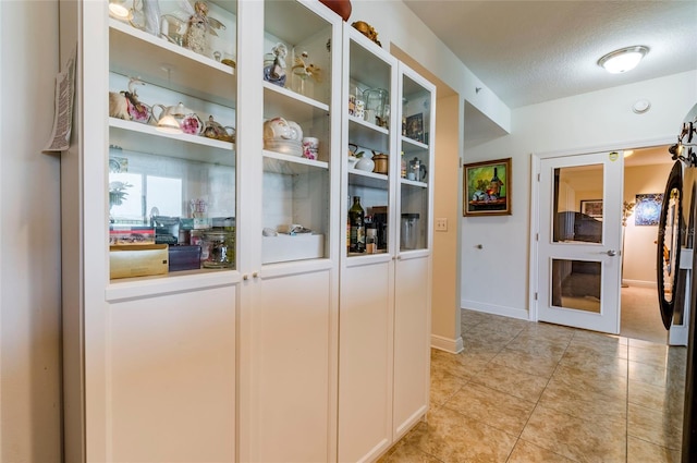 interior space featuring light tile patterned floors, baseboards, and a textured ceiling