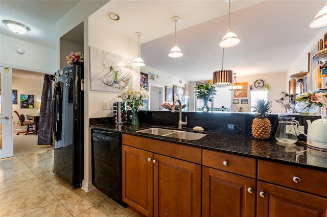 kitchen with black appliances, dark stone counters, brown cabinetry, and a sink