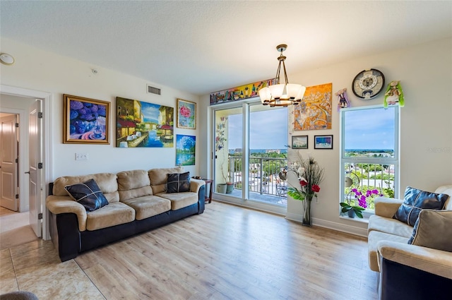 living room featuring a notable chandelier, light wood-style flooring, baseboards, and visible vents