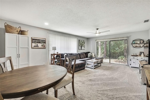 dining space featuring a textured ceiling, ceiling fan, and light carpet