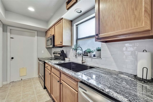 kitchen with backsplash, dark stone counters, light tile patterned flooring, stainless steel appliances, and a sink