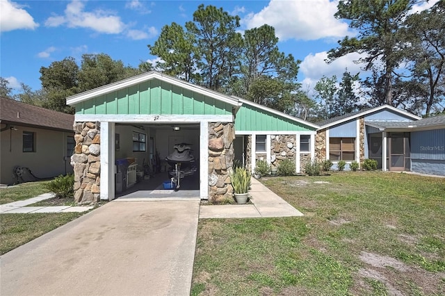 view of front of home featuring stone siding, board and batten siding, driveway, and a front yard