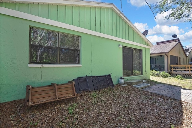 rear view of house with stucco siding and board and batten siding