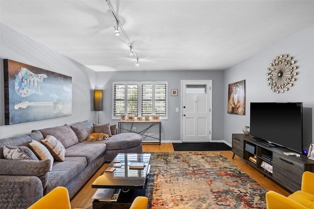 living room with rail lighting, wood finished floors, and baseboards