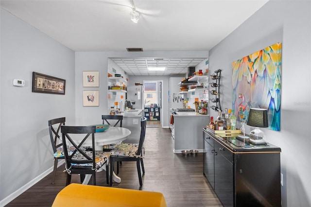 dining area featuring visible vents, a paneled ceiling, dark wood-type flooring, and baseboards