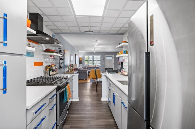 kitchen featuring dark wood finished floors, appliances with stainless steel finishes, wall chimney range hood, and open shelves