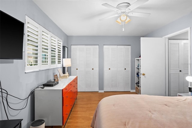 bedroom featuring a ceiling fan, light wood-style floors, and two closets