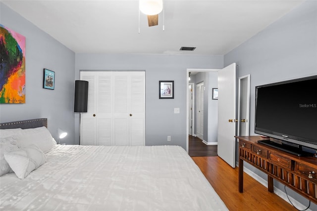 bedroom with visible vents, baseboards, wood finished floors, a closet, and a ceiling fan