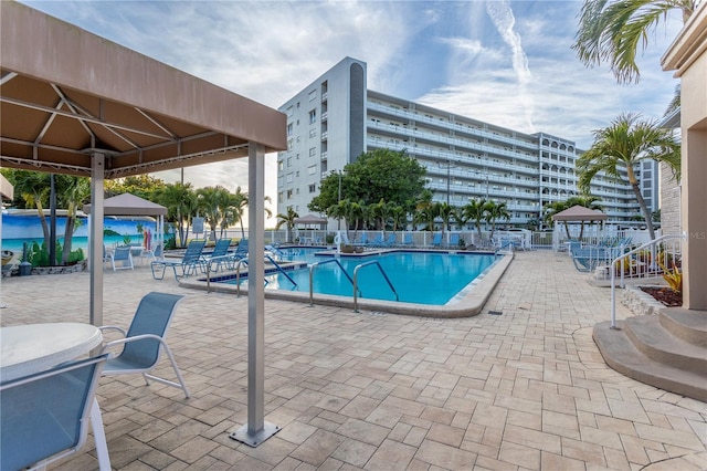 community pool with a gazebo, fence, and a patio