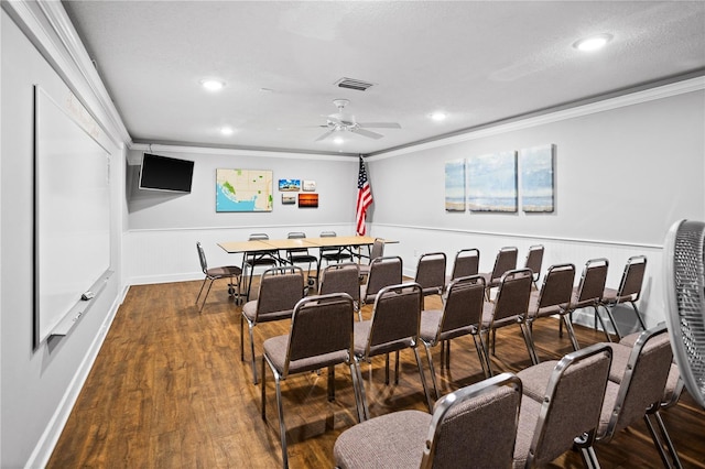 home theater with a ceiling fan, visible vents, dark wood-style flooring, wainscoting, and crown molding