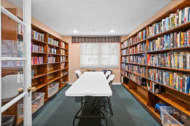 carpeted office space featuring baseboards and wall of books