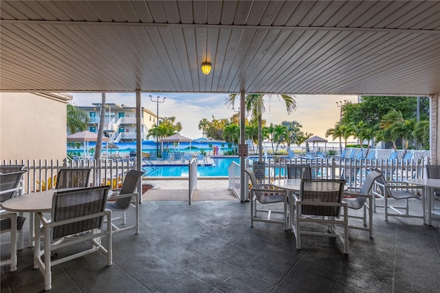 view of patio with outdoor dining area, a community pool, and fence