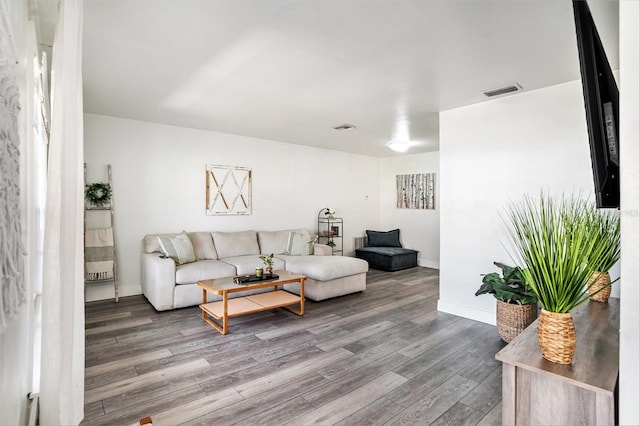 living room with visible vents, baseboards, and wood finished floors