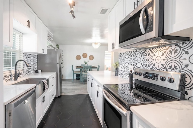 kitchen with tasteful backsplash, visible vents, appliances with stainless steel finishes, white cabinetry, and a sink