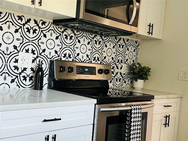 kitchen featuring light stone counters, appliances with stainless steel finishes, and white cabinetry