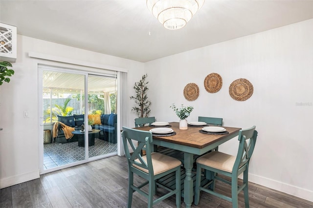 dining room featuring a chandelier, baseboards, and wood finished floors