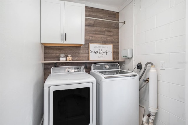 laundry area with cabinet space, wood walls, and washer and clothes dryer