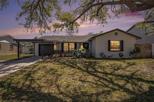 ranch-style home featuring an attached garage, a front lawn, fence, a carport, and driveway