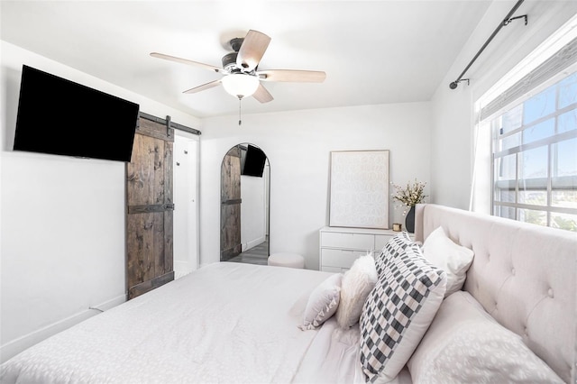 bedroom with a barn door and a ceiling fan