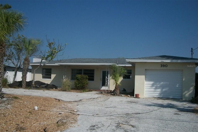 ranch-style house with a garage, driveway, and stucco siding