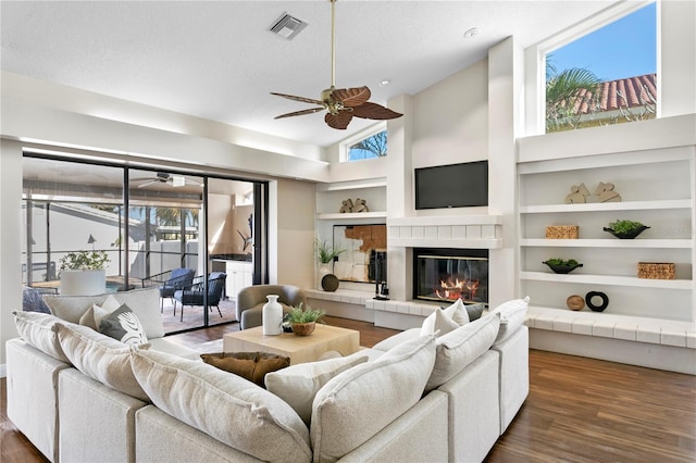 living room with visible vents, wood finished floors, a ceiling fan, and built in features