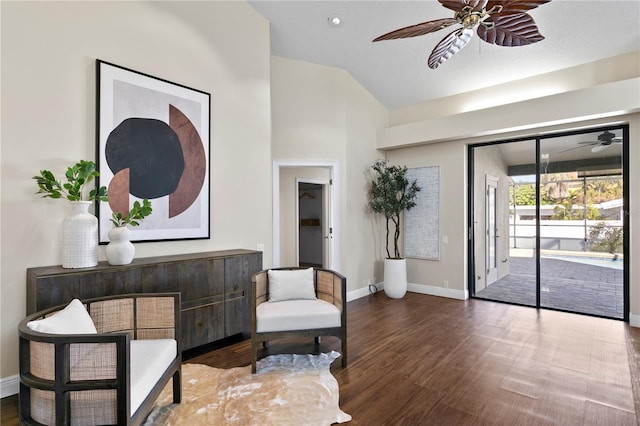 living area with baseboards, lofted ceiling, a ceiling fan, and wood finished floors