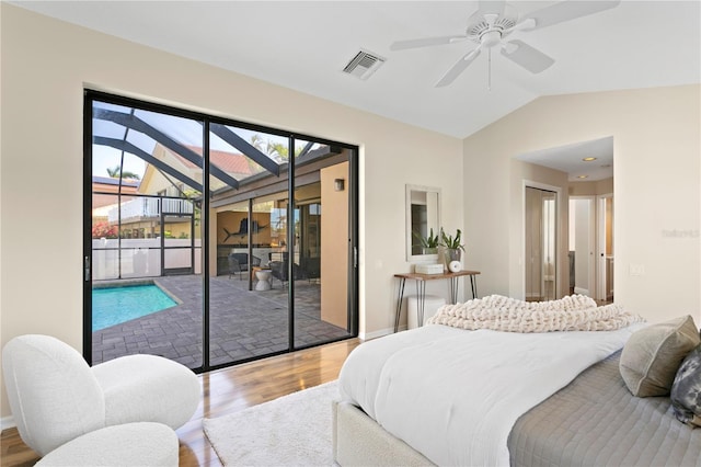 bedroom featuring access to exterior, visible vents, a sunroom, vaulted ceiling, and wood finished floors